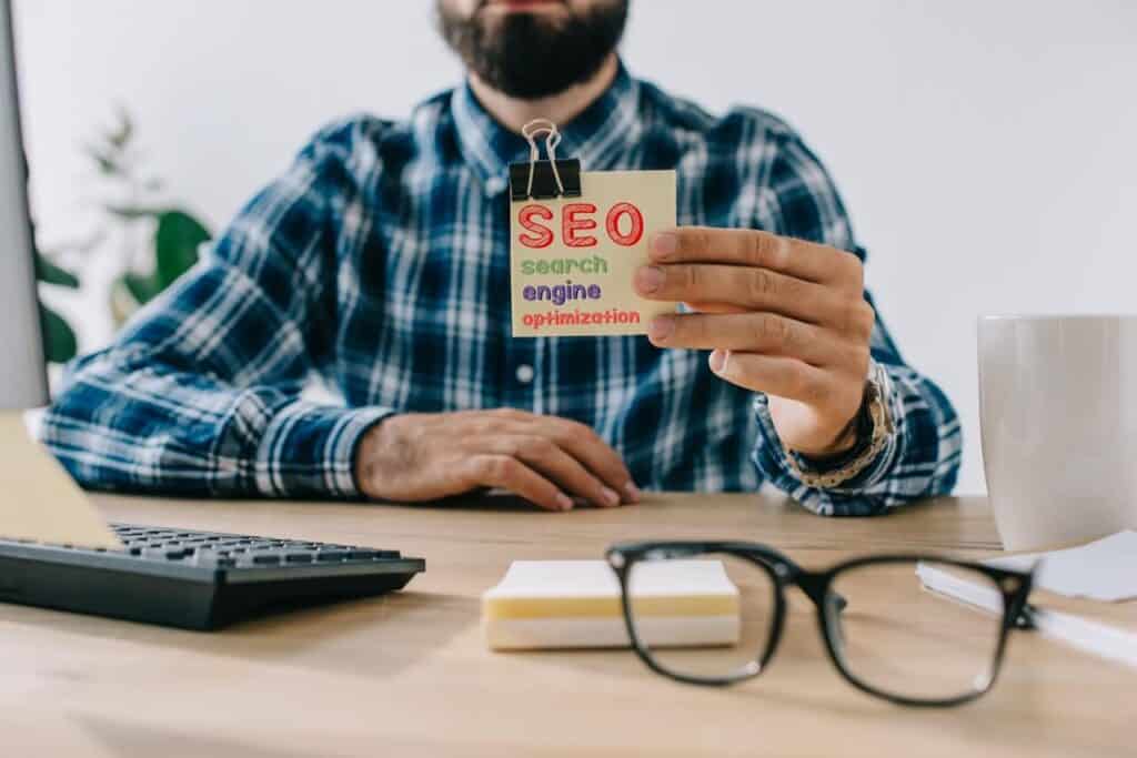 Man at a desk holding a card that says SEO